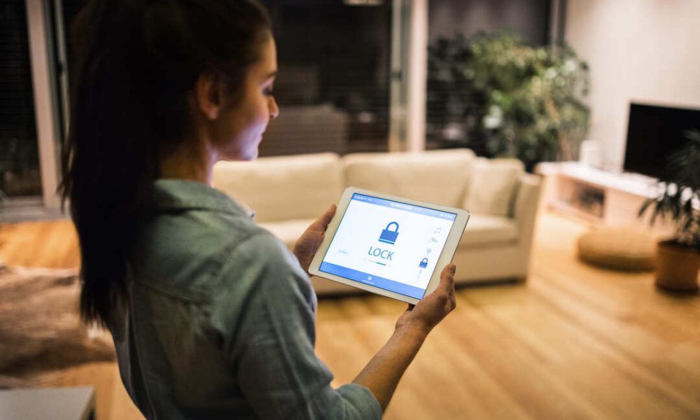 femme-tenant-une-tablette-de-securite-connecte Une femme qui vérifie son alarme